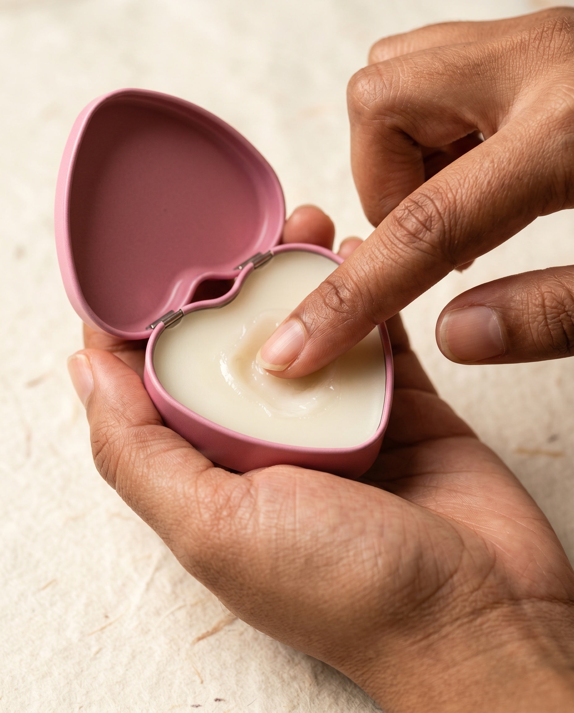 A fingertip pressing into the wax balm.